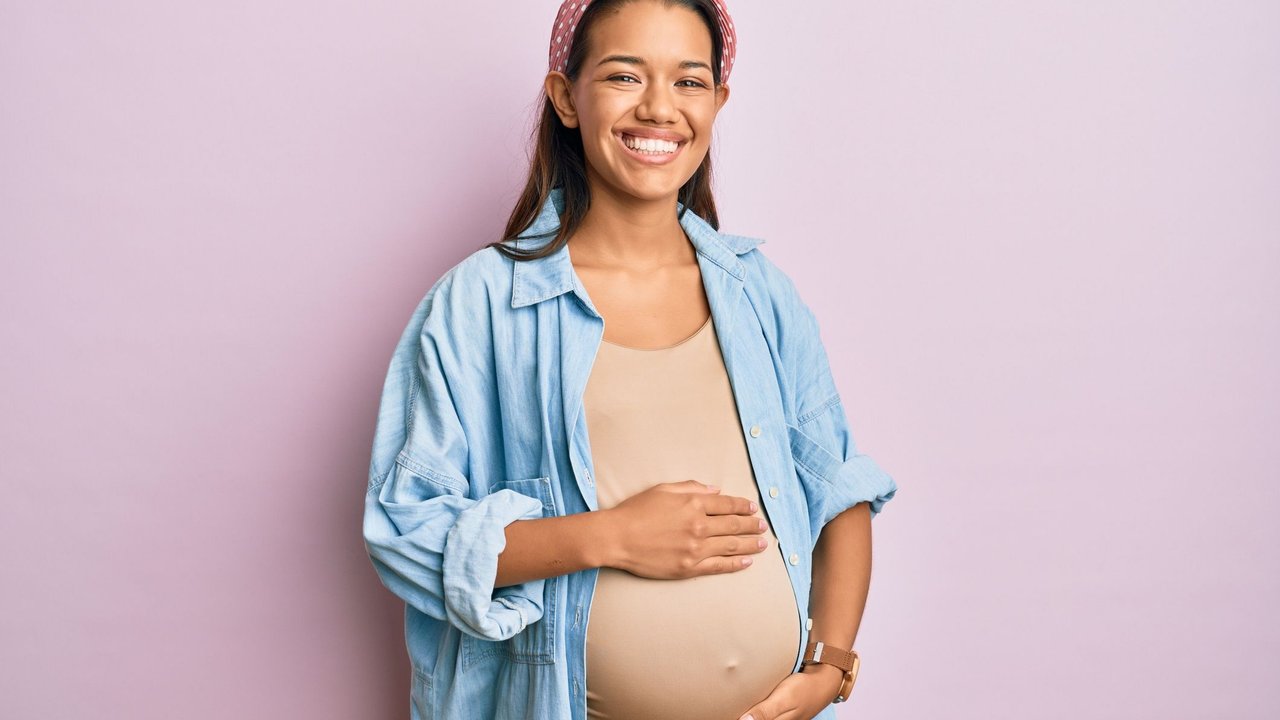 Schwangerschaft Körper: Schwangere hält sich lächelnd den Bauch
