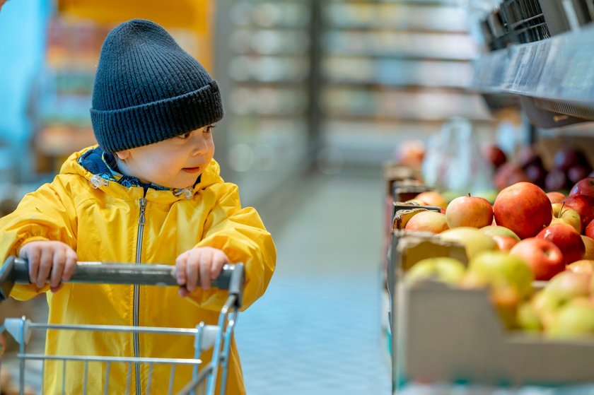 Kind mit Einkaufswagen im Supermarkt