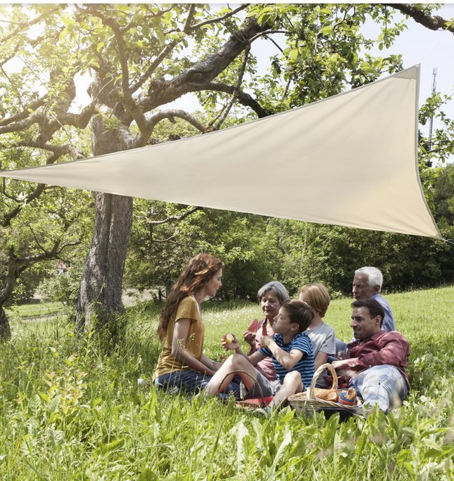 Familie sitzt in der Sonne auf einer Wiese unter einem Sonnensegel