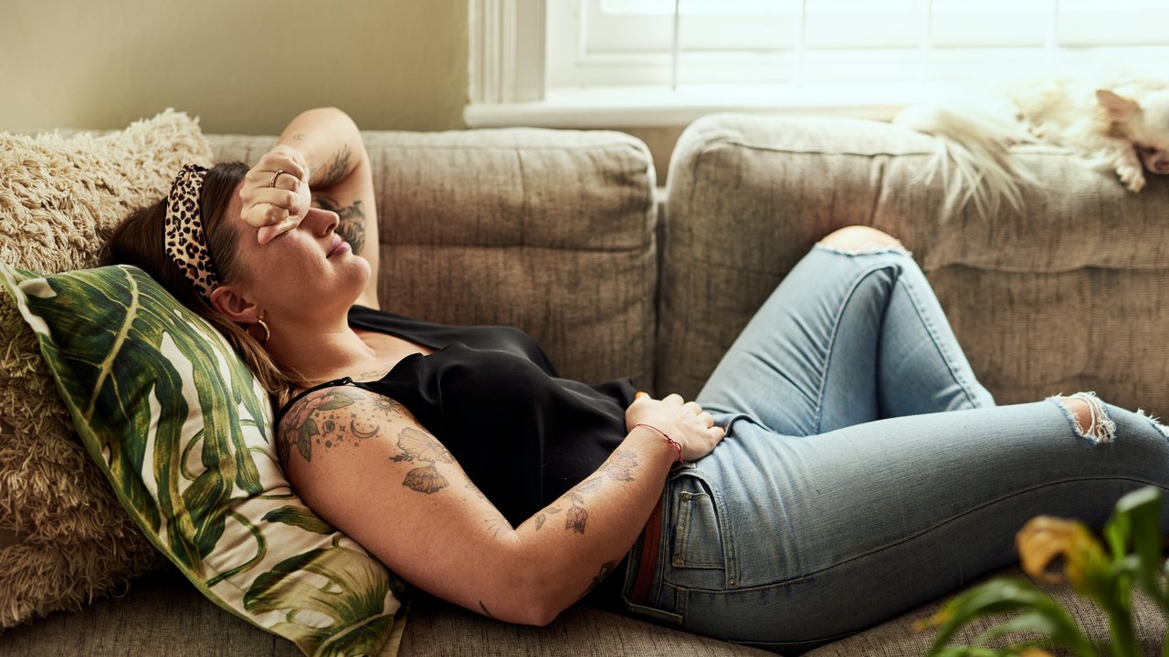 Einnistungsblutung: Schwangere liegt auf der Couch