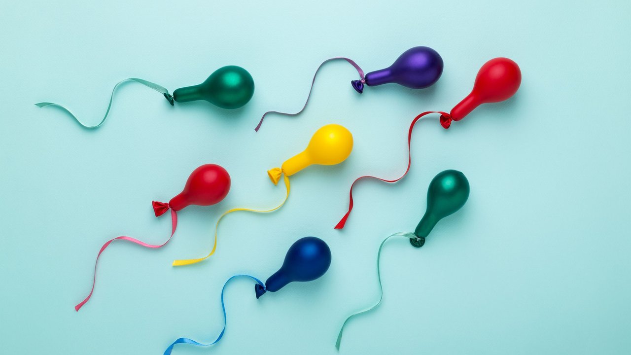 Bunte Luftballons in Spermienform auf blauem Hintergrund