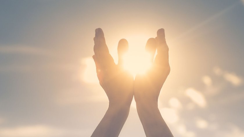 Karma-Sprüche: Sonne scheint durch zwei Hände, Himmel im Hintergrund