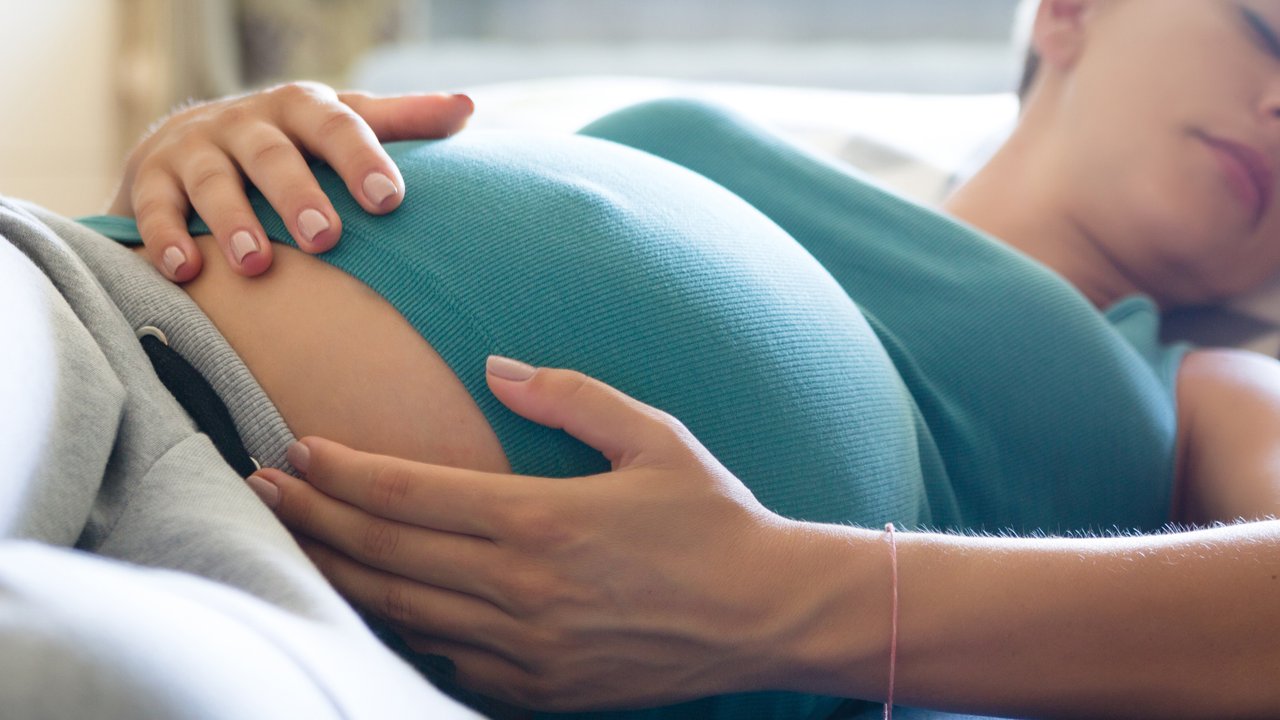 Photo of pregnant woman sleeping on the blue couch