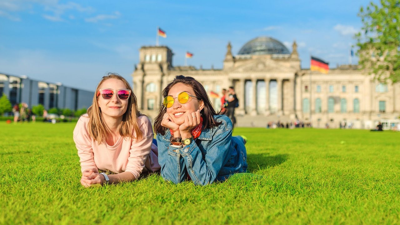 Zwei junge Studentinnen liegen vor dem Bundestag in der Sonne und lachen