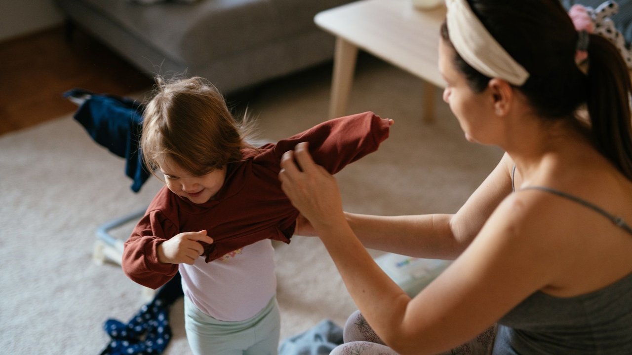 Kind Übergänge erleichtern: Mama hilft Kind beim Anziehen