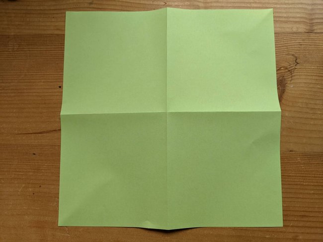 Tannenbaum falten: Aufgeklapptes quadratisches Papier mit Falzkreuz.