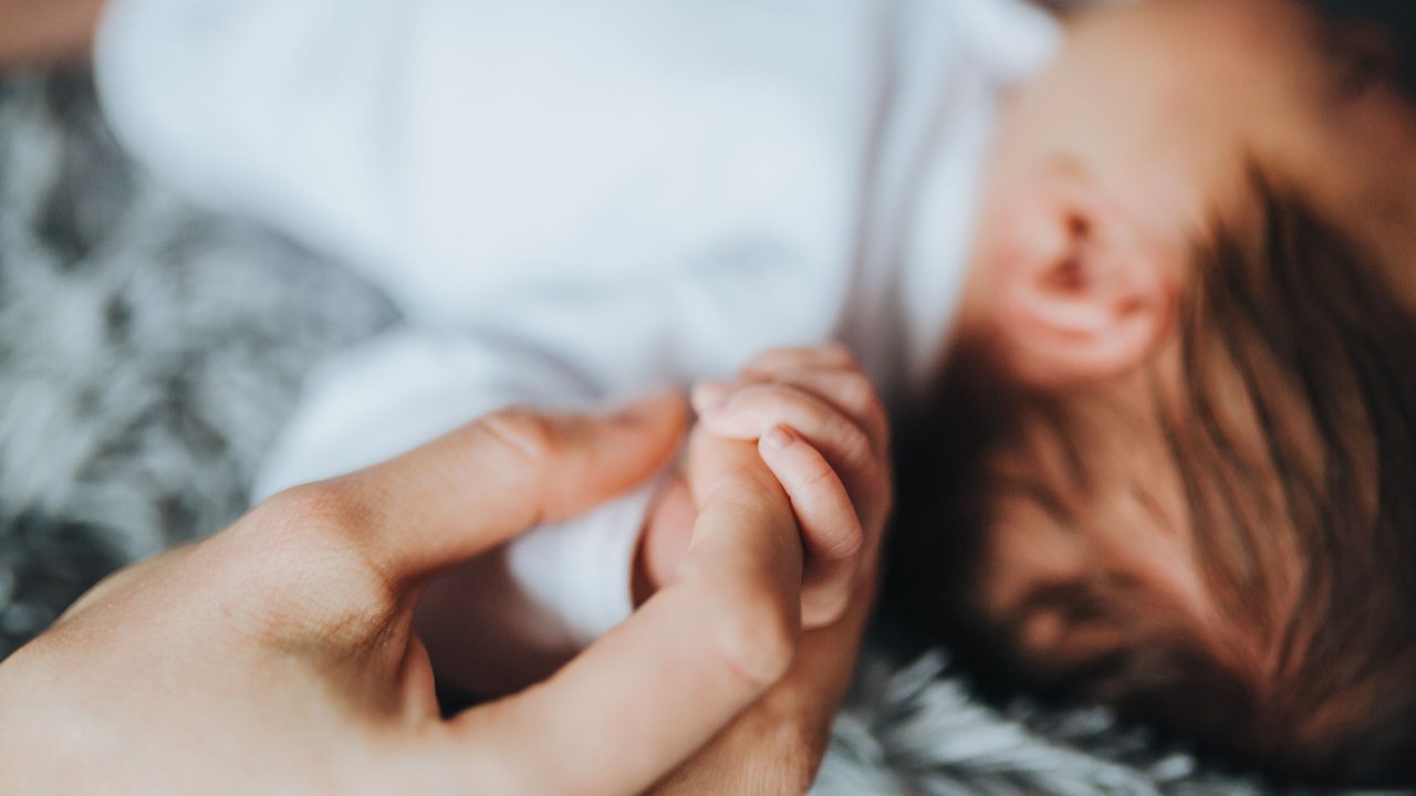 Sprüche zur Geburt: Erwachsene Hand hält Babyhand