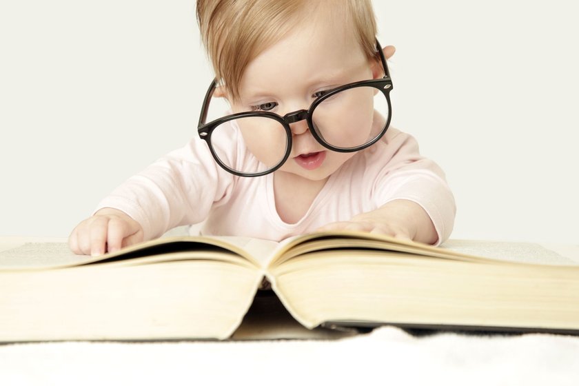 Baby mit Brille, das einen Wälzer liest