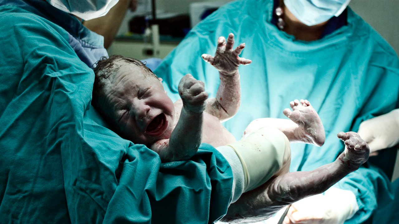 A doctor holding a beautiful baby boy minutes after the birth.