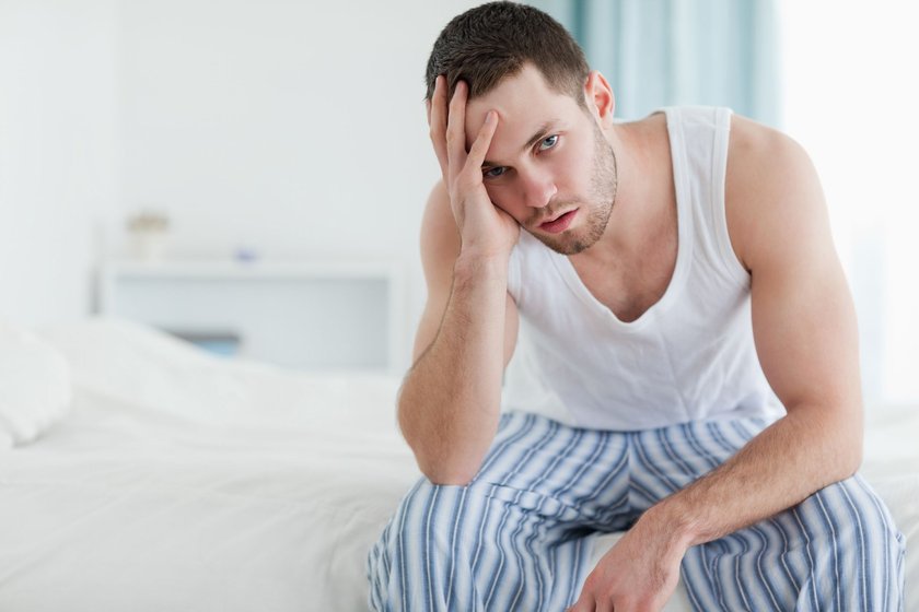 Männer & Lustlosigkeit: Mann sitzt deprimiert auf Bett