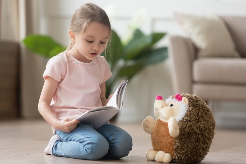 Geschenke für Mädchen: Mädchen liest ihrem Kuscheltier eine Geschichte vor