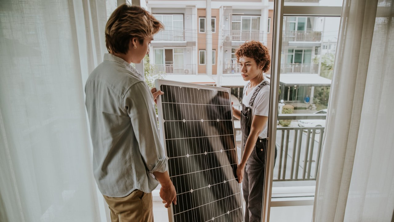 Two Thai nonbinary people are settings solar panel on balconies of houses for environment friendly.