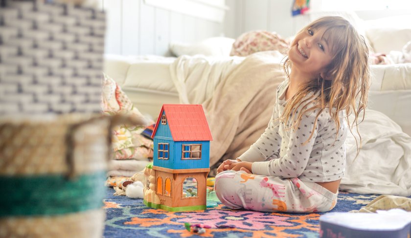 Aufräumen mit Kindern Fehler: Kind spielt lachend in Kinderzimmer
