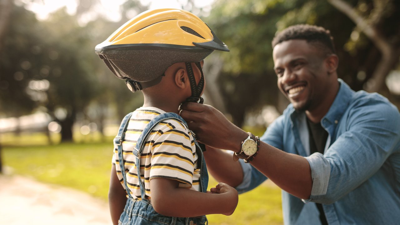 Kinderfahrradhelme im Test: Vater setzt seinem Kind einen Helm auf