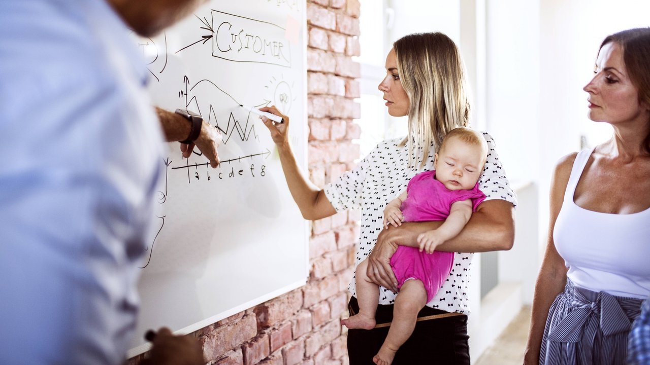 Vereinbarkeit: Mutter im Job mit Baby auf dem Arm