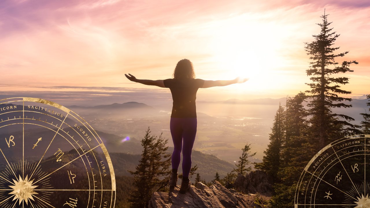 Frau steht mit ausgebreiteten Armen an einem Berggipfel bei Sonnenaufgang