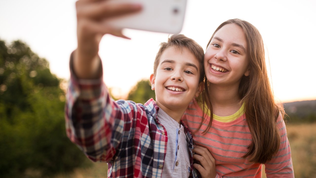 Photo of children take selfie with a smart phone in nature getty/ mixetto