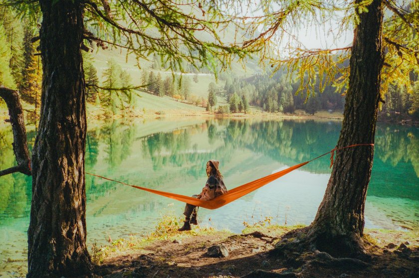 Junge Frau sitzt auf einer Hängematte am See