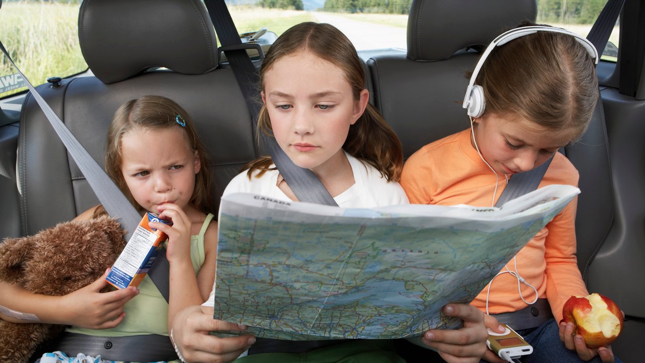Three girls (6-8 years) sitting on rear seat of car during road trip