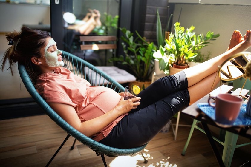 Schwangere Frau chillt auf dem Balkon