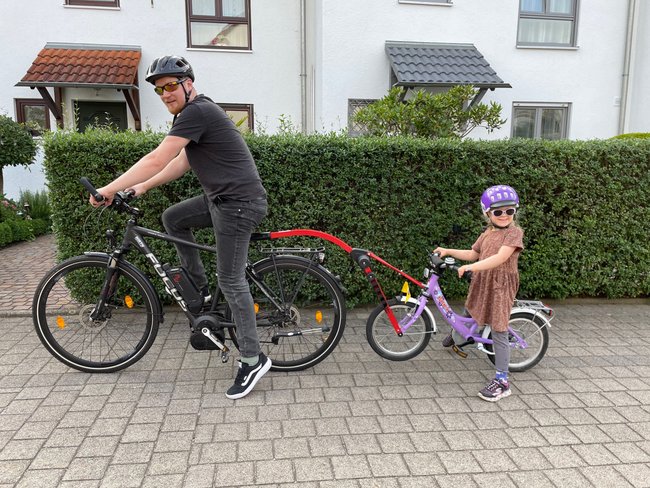 Tandemstange Fahrrad: Vater und Tochter sitzen auf Fahrrädern verbunden mit dem Trail Angel