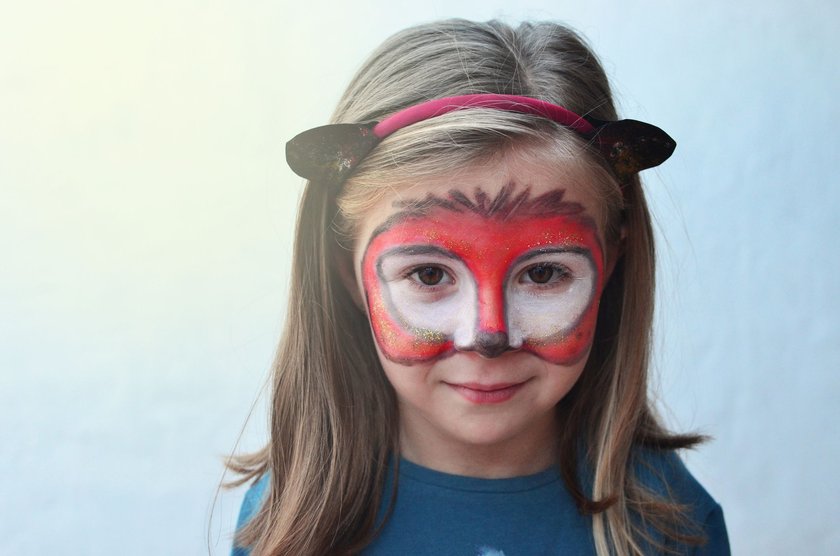 Portrait of a little girl with a face painted like a fox