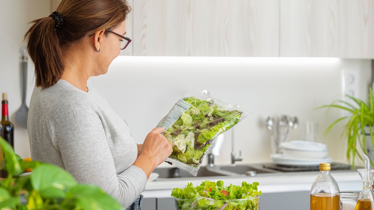Frau schaut sich abgepackten Salat an