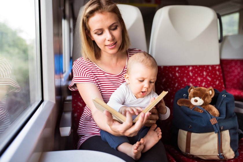 Mutter und Baby gucken ein Buch im Zug an