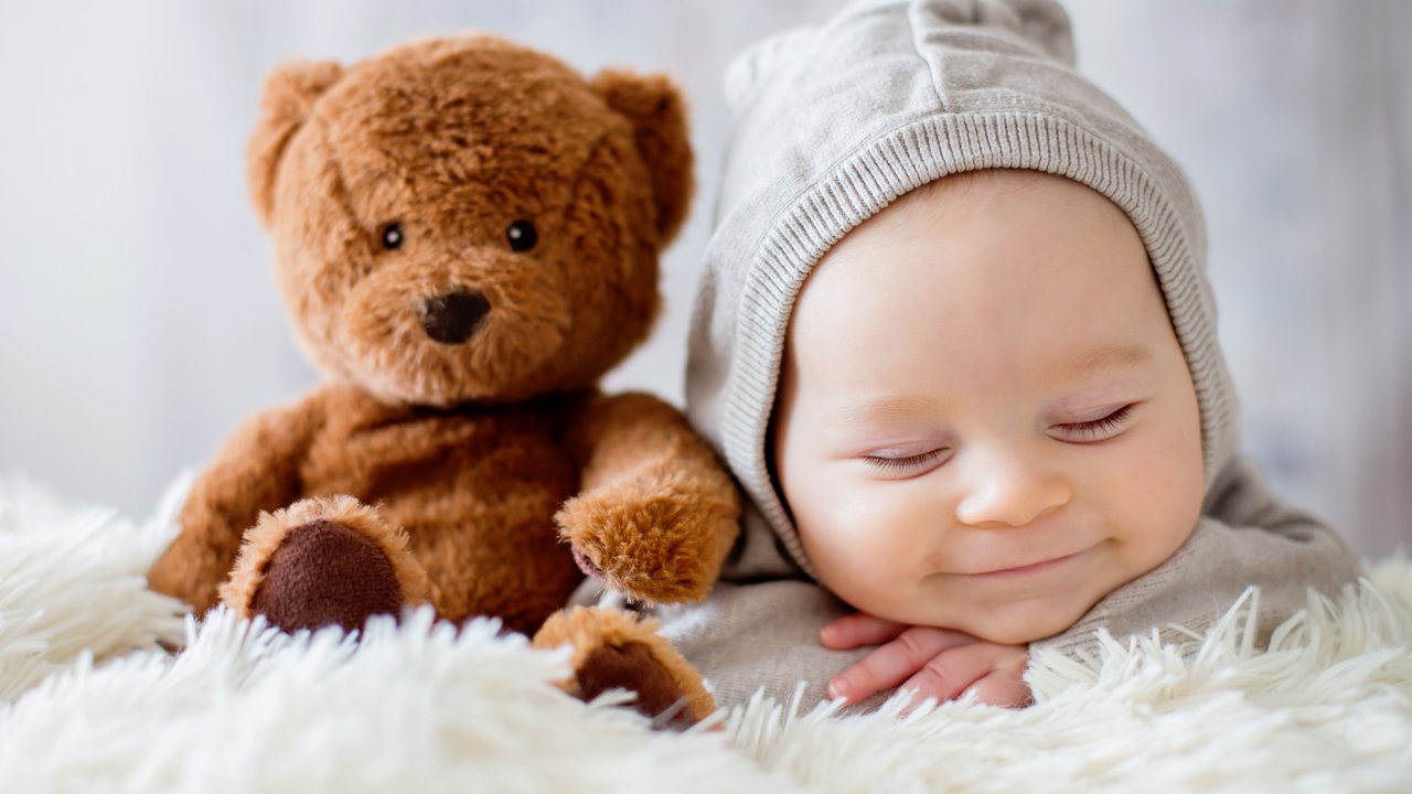 Neugeborenes Baby schläft zufrieden mit seinem Teddy