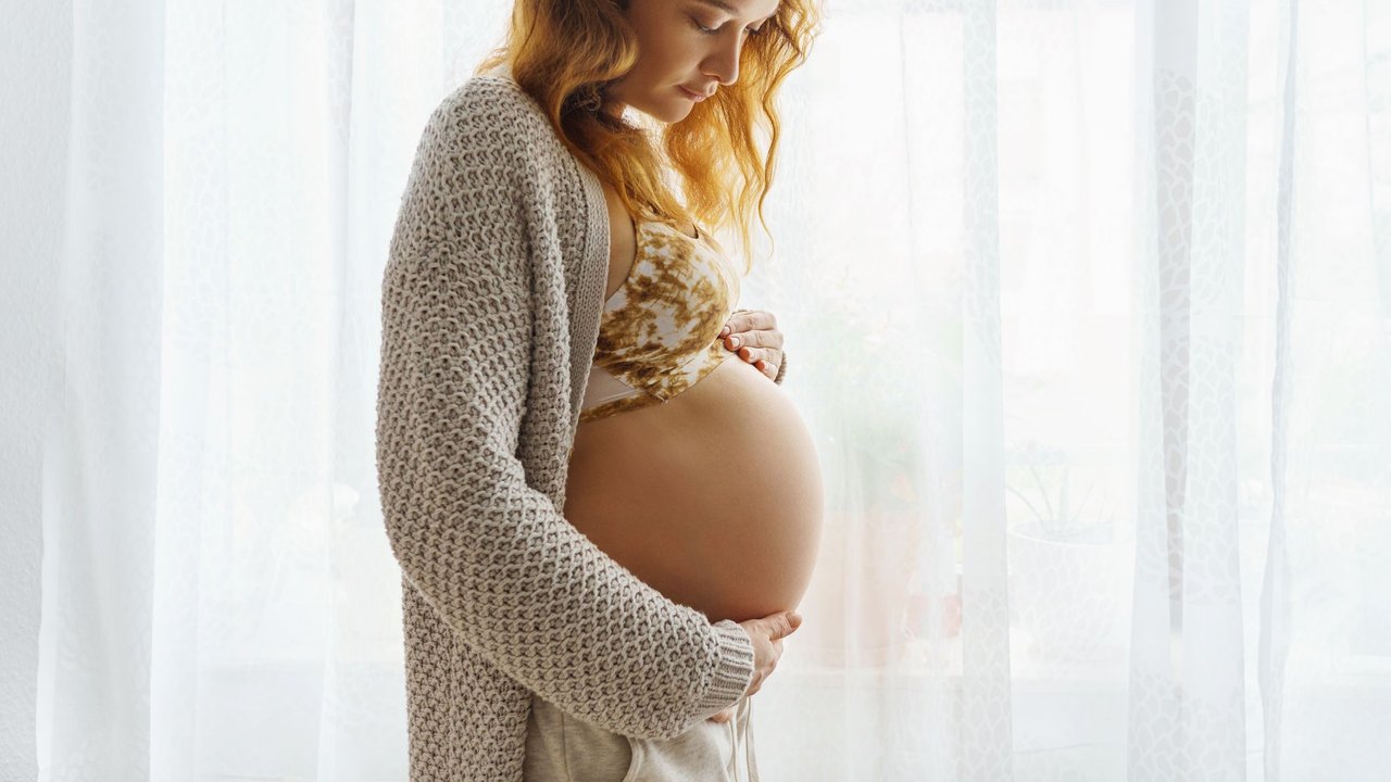 Geburt einleiten: Schwangere streichelt ihren Babybauch