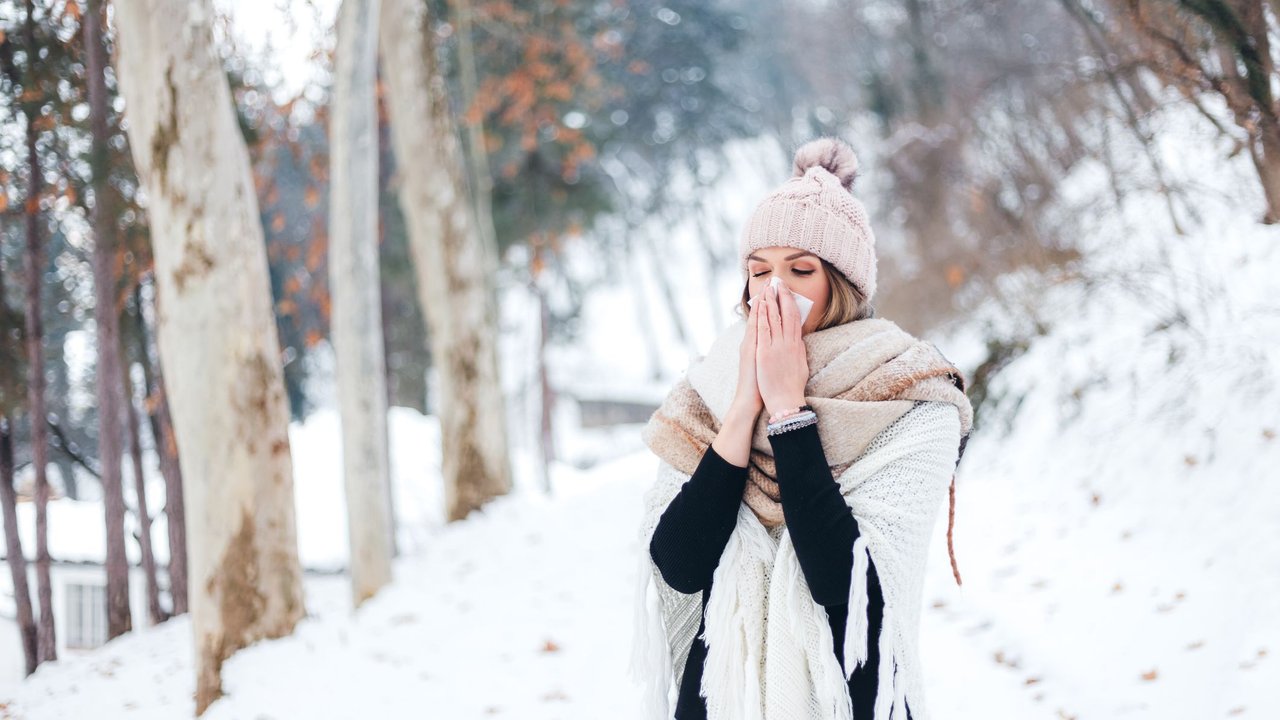 Junge Frau mit Schnupfen im Schnee