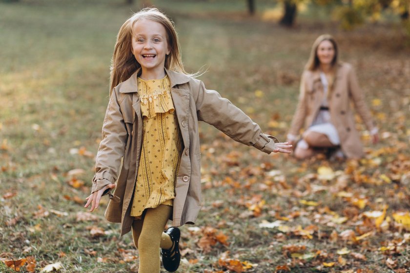 Happy mother and her beautiful daughter have fun and walk in the autumn park.