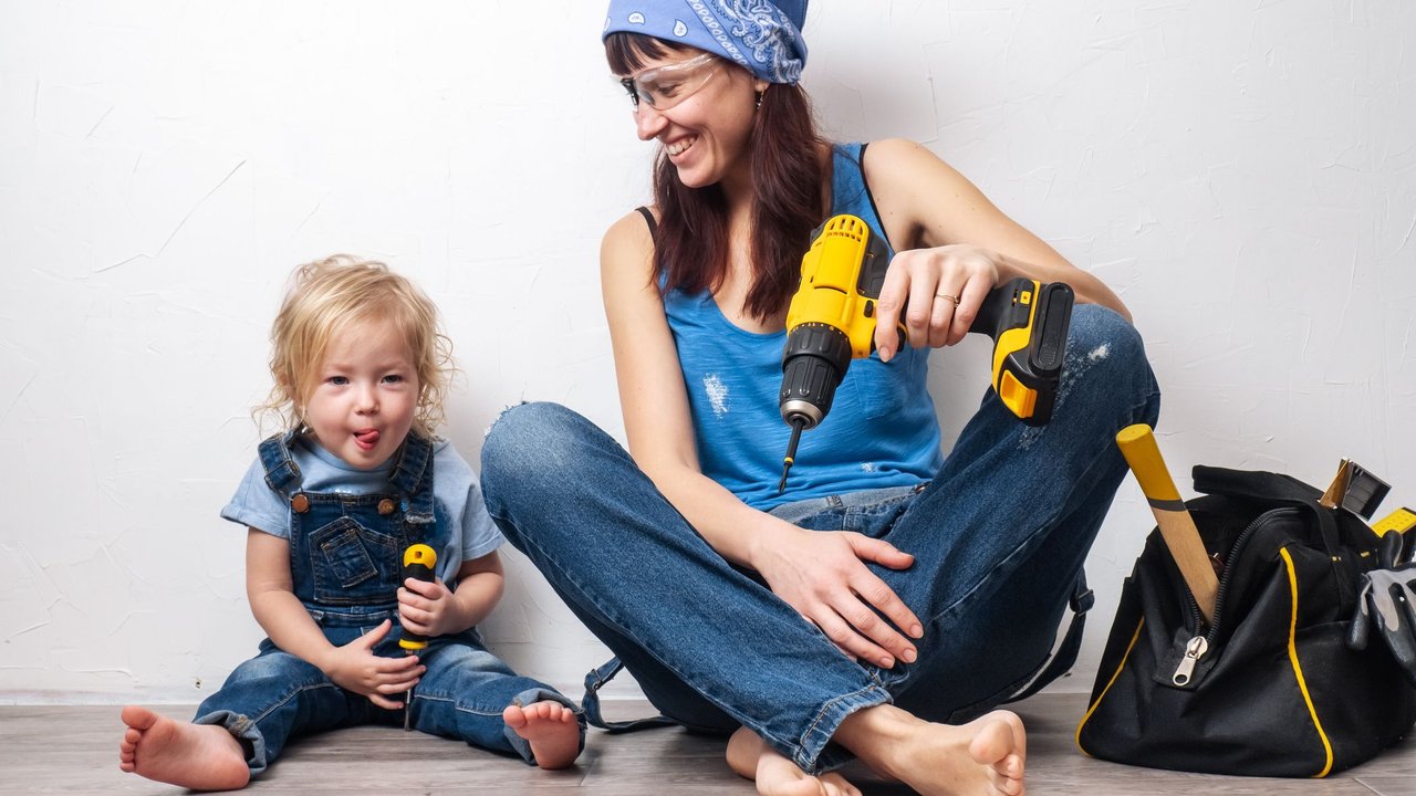 One parent: Mom performs men's housework with a small daughter and sat down to rest at the white wall. Portrait.