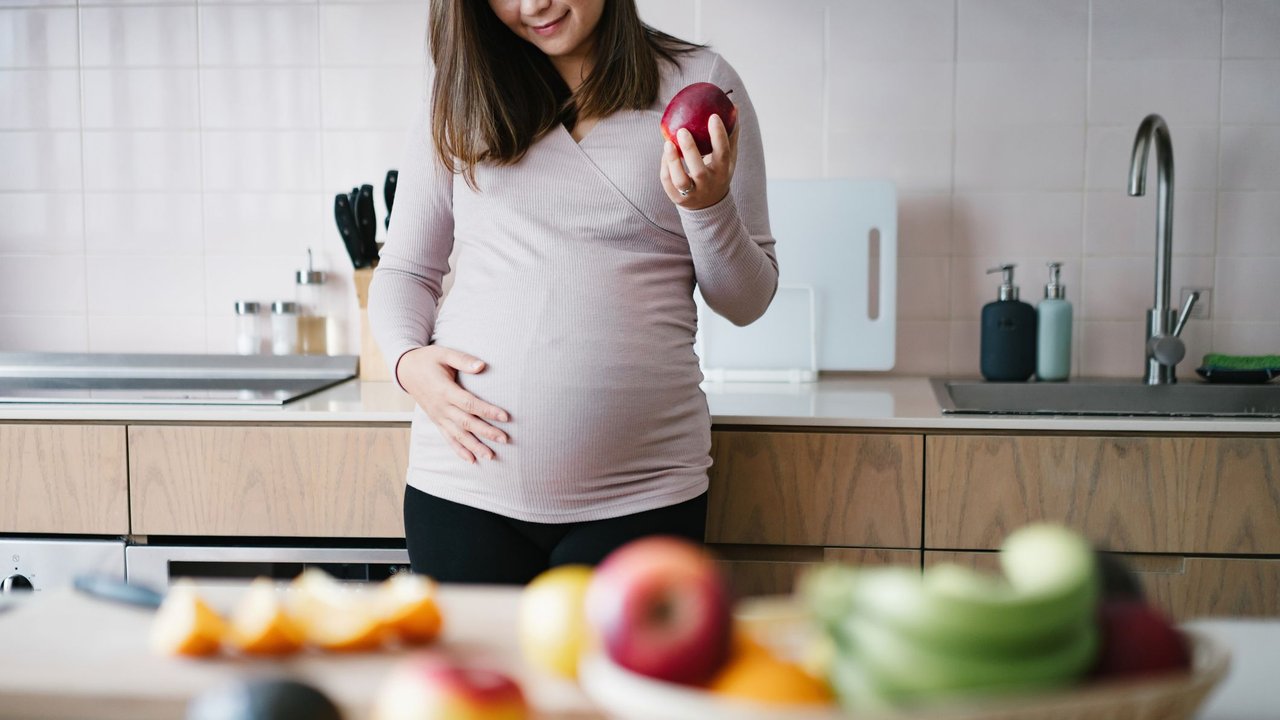 Obst in der Schwangerschaft: Schwangere hält Apfel in der Hand